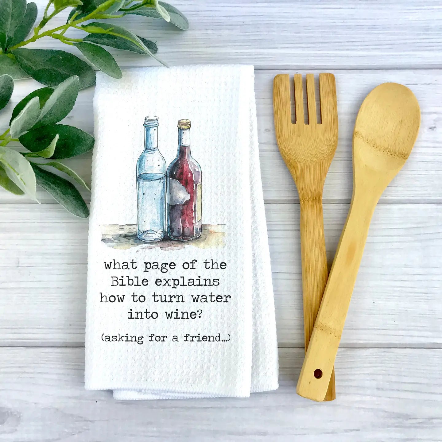 Towel with a question about turning water into wine, wooden fork and spoon on a light surface.