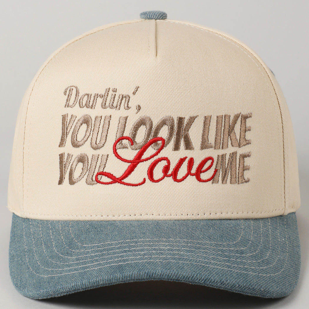 Cap with embroidered text 'Darlin', YOU LOOK LIKE YOU LOVE ME' on a gray background