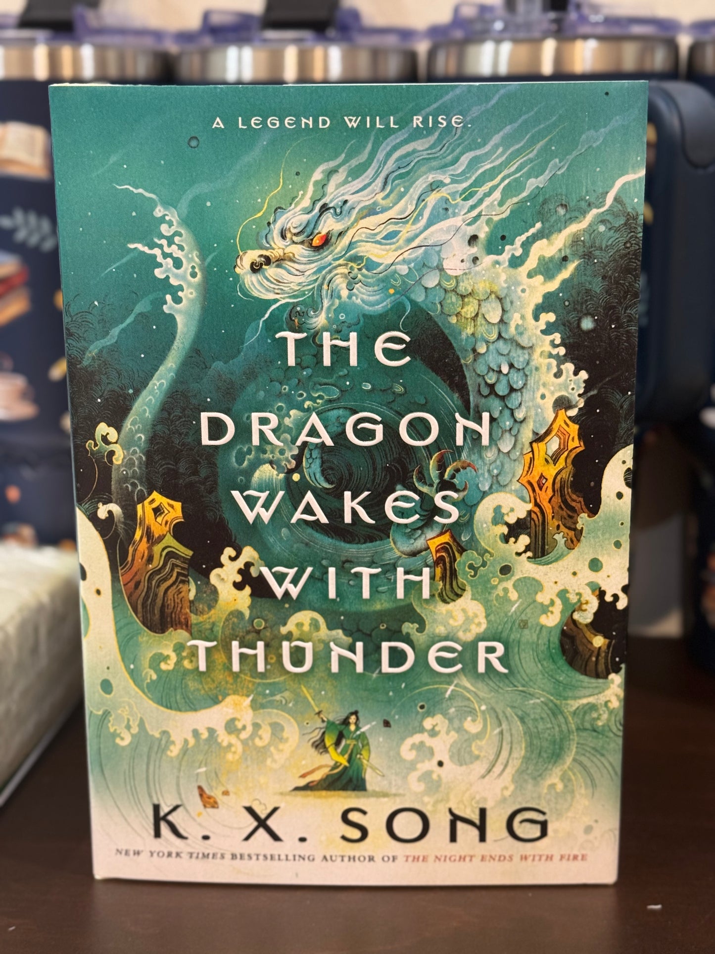 Book cover of 'The Dragon Wakes with Thunder' by K.X. Song on a dark surface.