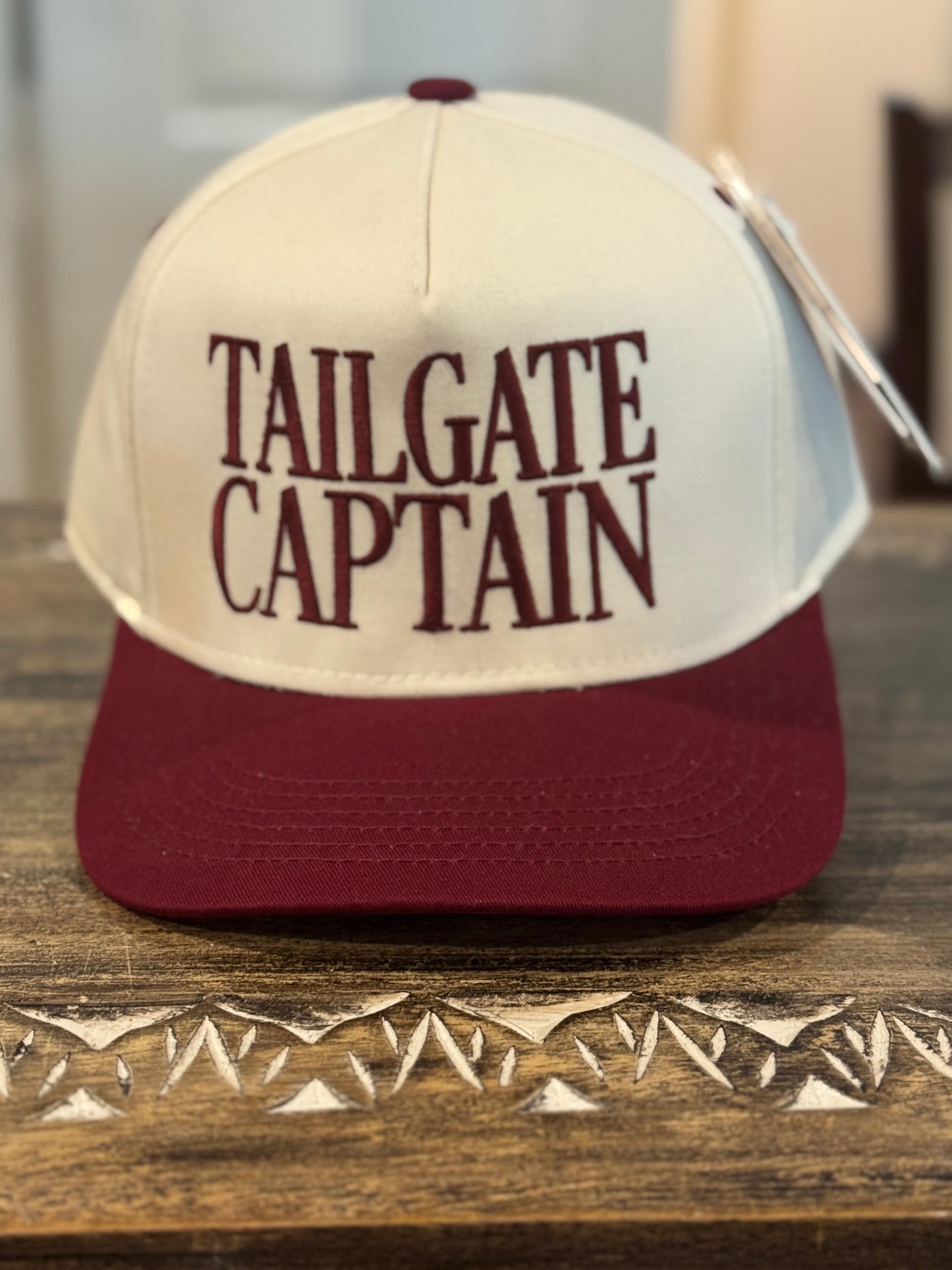 Cap with 'TAILGATE CAPTAIN' text on a wooden surface