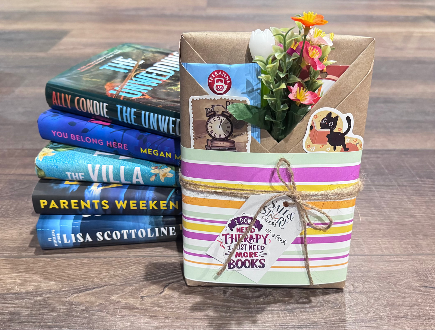 Stack of books with a decorative box containing flowers on a wooden surface