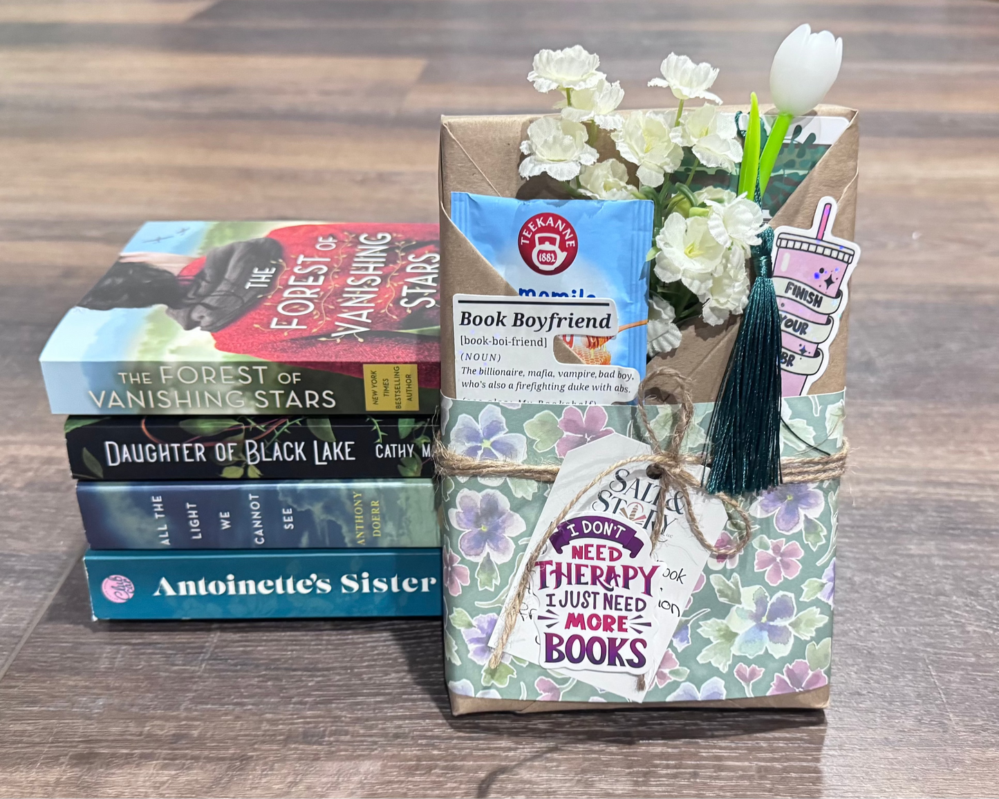Stack of books and a decorative box with flowers on a wooden surface