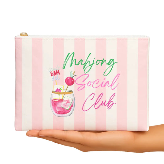 Pink and white striped pouch with 'Mahjong Social Club' text and cocktail graphic held by a hand.