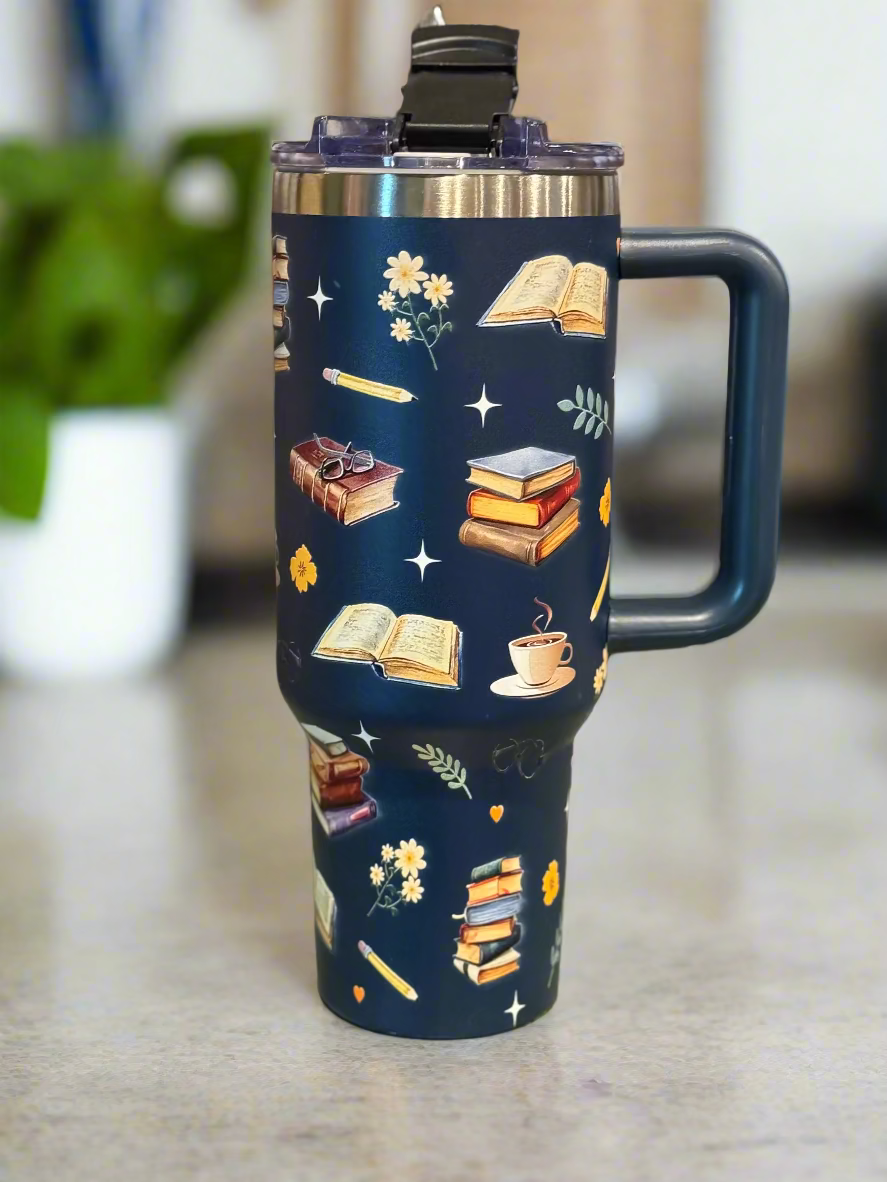 Navy blue tumbler with book-themed design on a wooden surface.