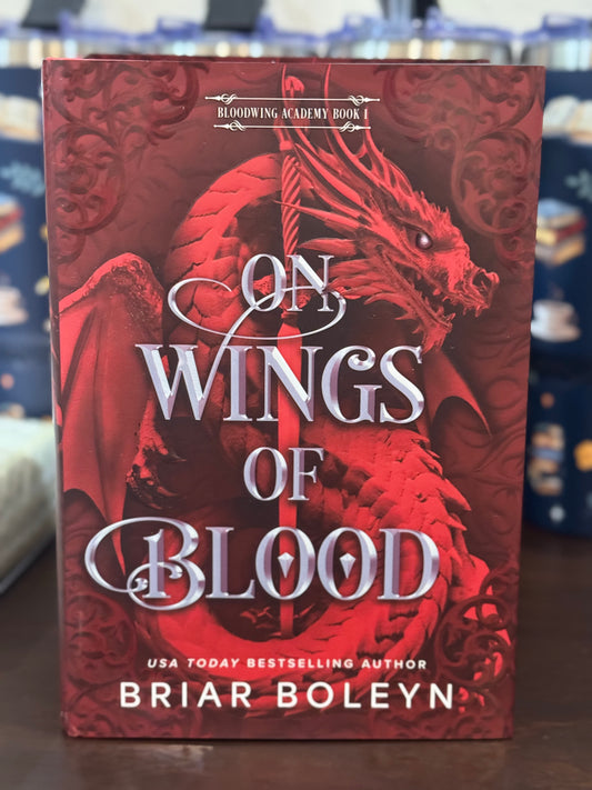 Book titled 'On Wings of Blood' by Briar Boleyn with a red dragon design on the cover.