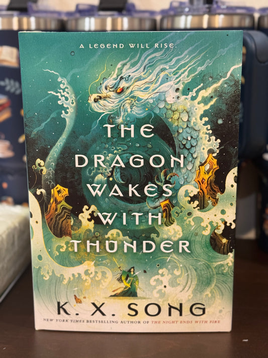 Book cover of 'The Dragon Wakes with Thunder' by K.X. Song on a dark surface.