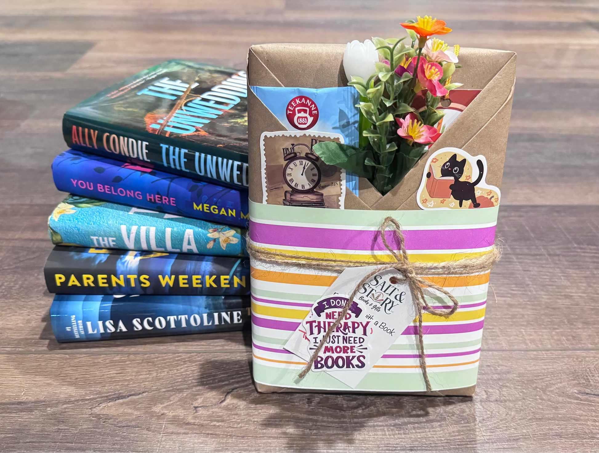 Stack of books with a decorative box containing flowers on a wooden surface