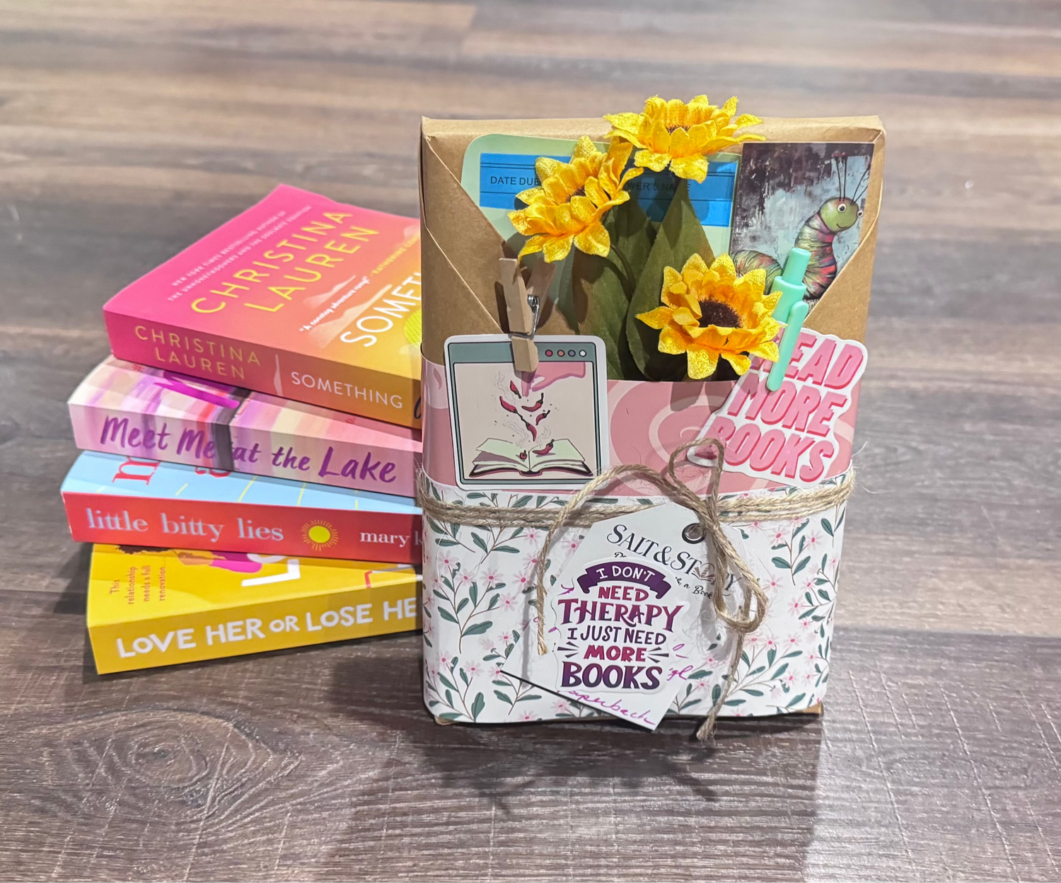 Stack of books with a decorative box and flowers on a wooden surface