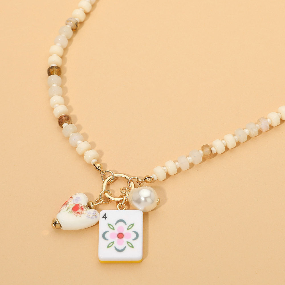 Necklace with heart and flower charm on a beige background