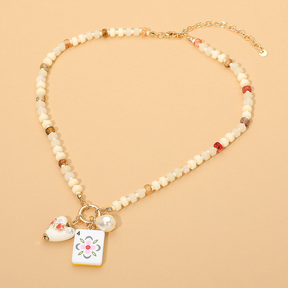 Necklace with beaded chain and floral charm on a beige background