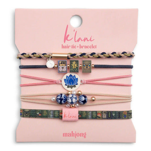 "K'lani Mahjong Hair Tie Bracelet Set featuring five colorful hair ties with mahjong tiles, blue lotus charm, beads, and woven bracelet designs."