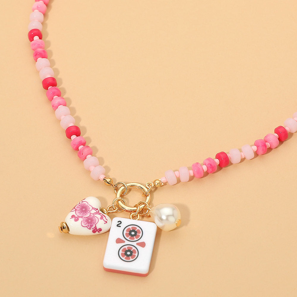 Necklace with pink beads and decorative charms on a beige background
