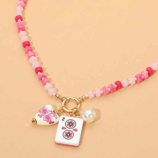 Necklace with pink beads and decorative charms on a beige background