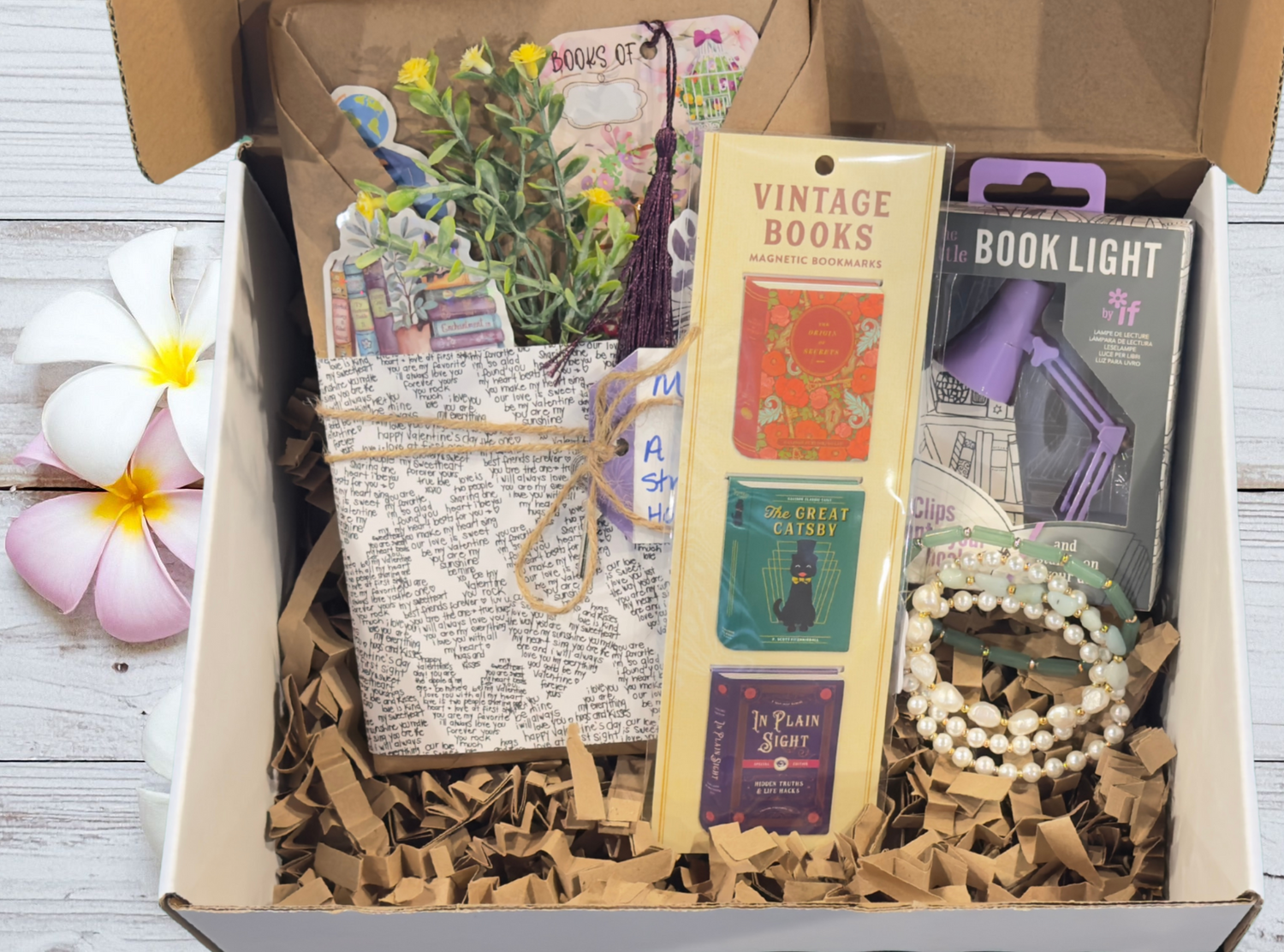 Box containing vintage books, a plant, and other items on a wooden surface.