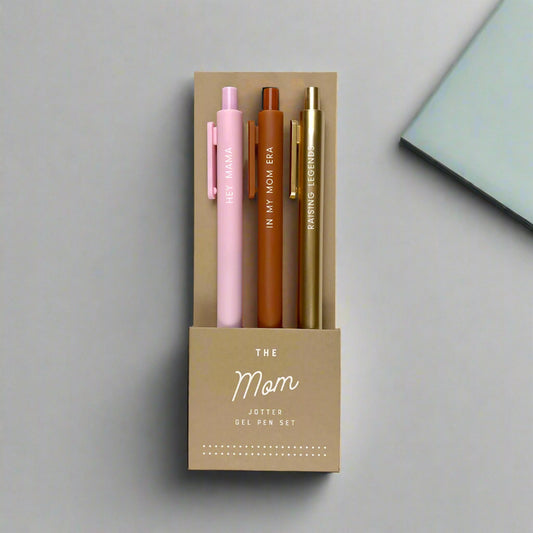 Set of three pens in pink, brown, and gold in a cardboard holder with 'The Mom Jotter Gel Pen Set' text.