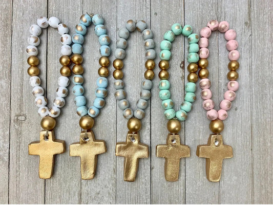 Set of five beaded necklaces with gold cross pendants on a wooden surface