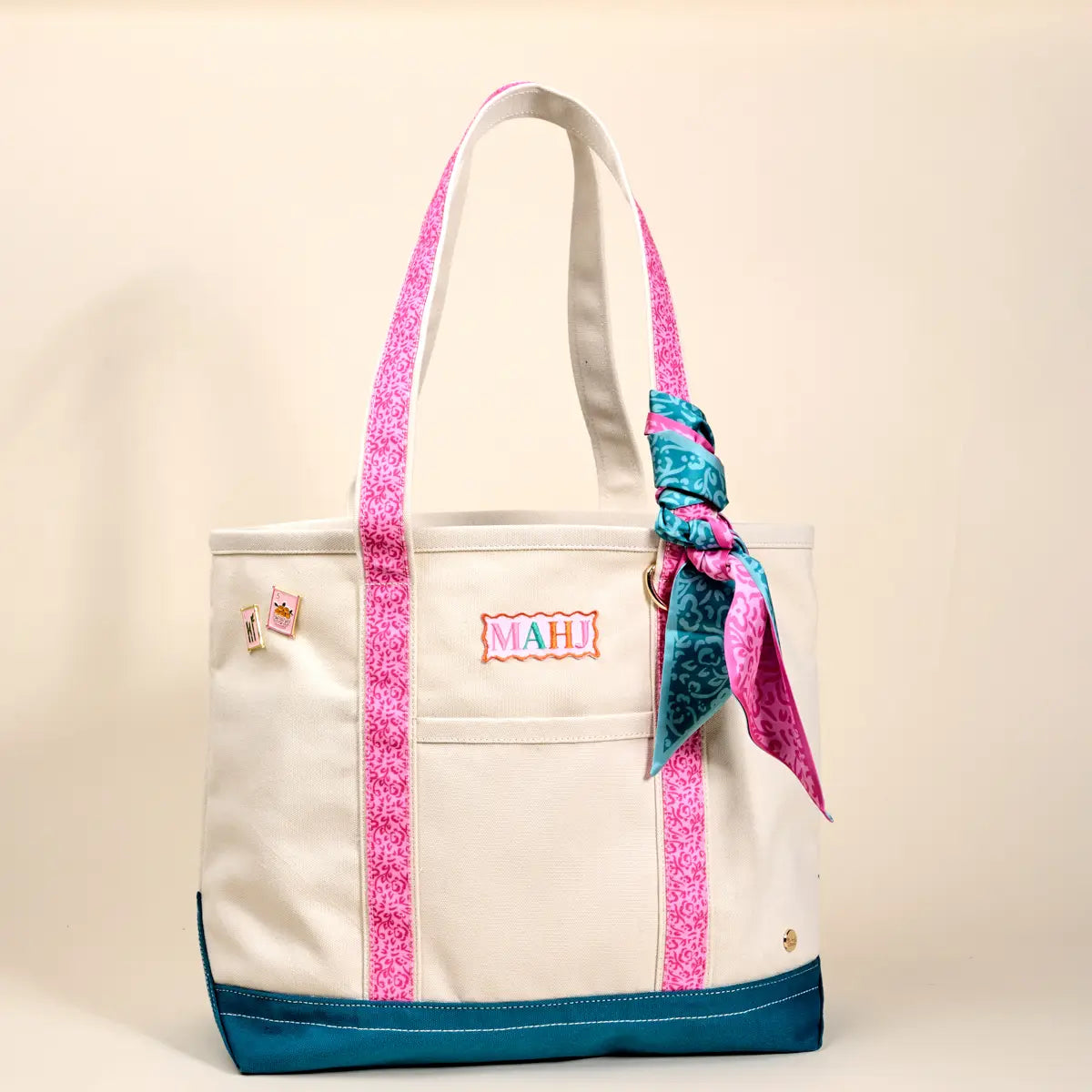 Beige tote bag with pink straps and a colorful bandana, on a beige background