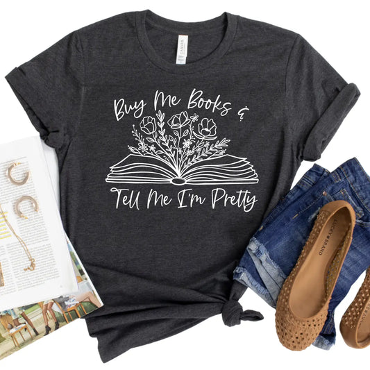 Dark gray t-shirt with floral book design and text, paired with jeans and shoes on a white background.